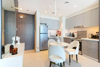 a kitchen with a table and chairs and a refrigerator at Sky-High Downtown 1BR Steps from Burj Khalifa in Dubai