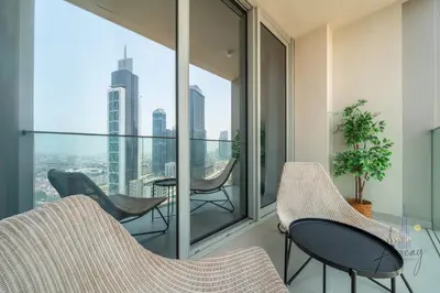 an apartment balcony with chairs and a view of the city at Sky-High Downtown 1BR Steps from Burj Khalifa in Dubai
