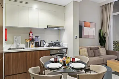 a kitchen and a living room with a table and chairs at Sleek 1BR Apt with Pool Gym by Dubai Canal, Dubai Mall & Business Bay in Dubai