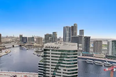 a building with a sign on top of it next to a river at Sleek 1BR Apt with Pool Gym by Dubai Canal, Dubai Mall & Business Bay in Dubai
