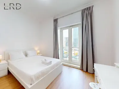 a bedroom with a white bed and a large window at Charming 1BR Apartment with Canal View in Business Bay in Dubai