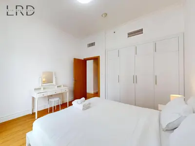 a white bedroom with a white bed and a desk at Charming 1BR Apartment with Canal View in Business Bay in Dubai