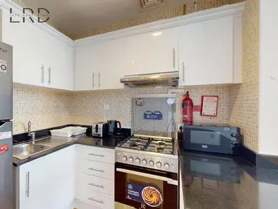 a kitchen with white cabinets and a stove top oven at Charming 1BR Apartment with Canal View in Business Bay in Dubai