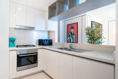 a white kitchen with a sink and a stove at Vibrant Luxe Burj Khalifa Views-Dubai Mall Access by Maxx Value Homes in Dubai