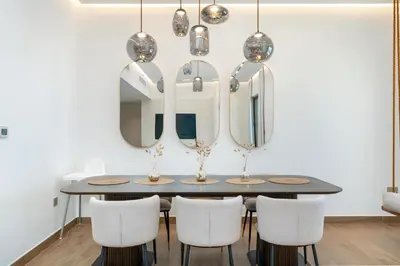 a dining room with a table with chairs and mirrors at King 2 Bedroom Jumeirah Beach & Dubai Eye Views in Dubai
