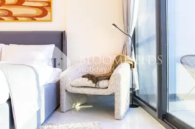 a cat sitting in a chair next to a bed at Bloomfields Charming Stu in Samana View in Dubai