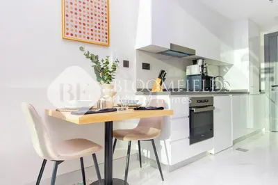 a kitchen with a wooden table and two chairs at Bloomfields Charming Stu in Samana View in Dubai