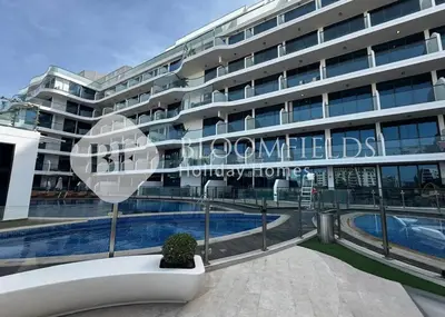 a large building with a swimming pool in front of it at Bloomfields Charming Stu in Samana View in Dubai