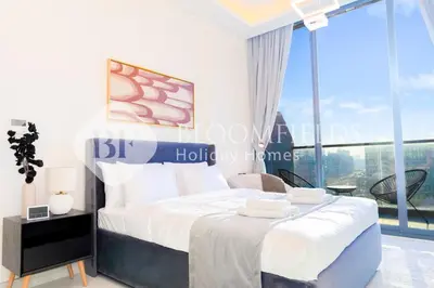 a bedroom with a large bed and a large window at Bloomfields Charming Stu in Samana View in Dubai