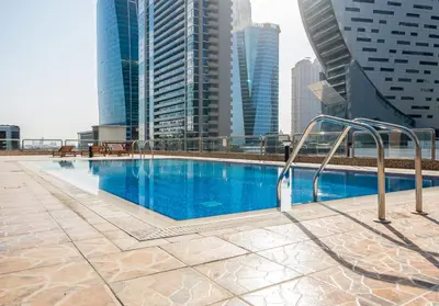a swimming pool on top of a building with tall buildings at Lavish 1 bedroom in Dubai