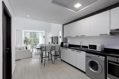 a kitchen with white cabinets and a table with chairs at Maison Privee - Sleek Stay in Dubai Marina Famous Twisting Tower in Dubai