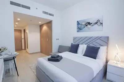 a white bedroom with a large bed and a table at Azizi Riviera 42 - Meydan by Golden Casa in Dubai