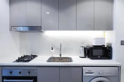 a white kitchen with a sink and a microwave at Azizi Riviera 42 - Meydan by Golden Casa in Dubai