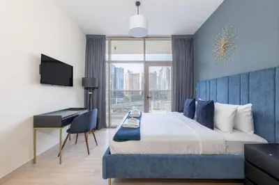 a bedroom with a bed with a desk and a window at Canal View, Partial Burj Khalifa View in Dubai