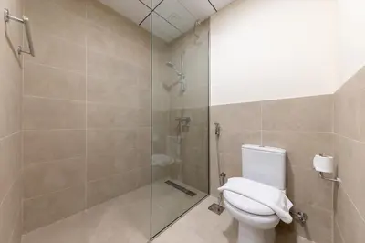 a bathroom with a toilet and a glass shower at Canal View, Partial Burj Khalifa View in Dubai