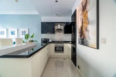 a kitchen with white cabinets and black appliances at GuestReady - Peaceful Skyline at Signature Tower in Dubai