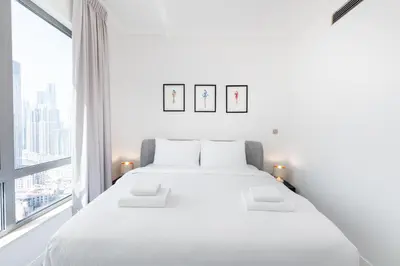 a white bedroom with a large white bed and a window at South Ridge 1, Downtown Dubai - Mint Stay in Dubai
