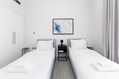 two beds in a room with white walls at South Ridge 1, Downtown Dubai - Mint Stay in Dubai
