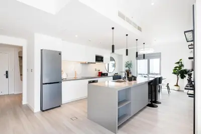 a white kitchen with a refrigerator and a counter at South Ridge 1, Downtown Dubai - Mint Stay in Dubai