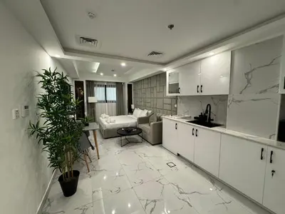 a kitchen with white cabinets and a living room at Modern & Stylish Studio Retreat in Dubai