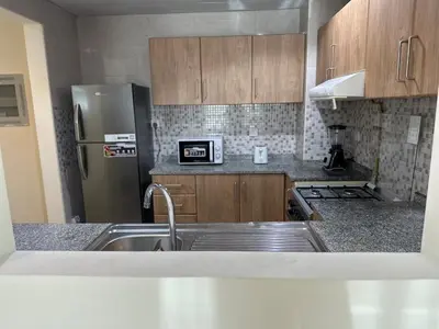 a kitchen with wooden cabinets and a stainless steel refrigerator at 1BR Apartment with Private Jacuzzi in JVC - JLiving in Dubai