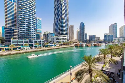 a boat in a river in a city with tall buildings at Luxurious 2Bed in Sparkle Tower-Marina View in Dubai