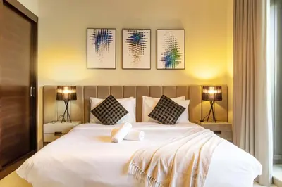 a bedroom with a large white bed with three pictures on the wall at Luxurious 2Bed in Sparkle Tower-Marina View in Dubai