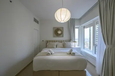 a white bedroom with a large bed and a large window at Luxury Apartment with Full Burj & Fountain Views in Dubai