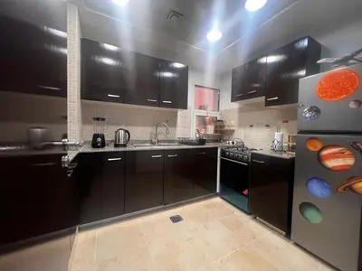 a kitchen with black cabinets and stainless steel appliances at New 1BED Apartment in Remraam, Dubai Land, Motor city, Damac hills, Mudoon area in Dubai