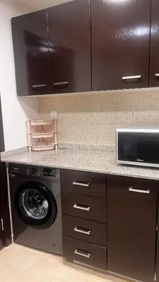a kitchen with a washing machine and a microwave at New 1BED Apartment in Remraam, Dubai Land, Motor city, Damac hills, Mudoon area in Dubai