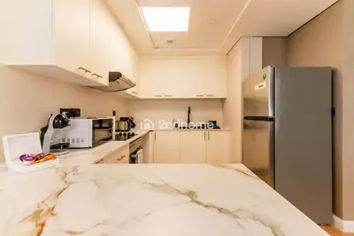 a kitchen with white cabinets and a stainless steel refrigerator at Stylish 2Bedroom in DIFC Dubai Newly Furnished in Dubai