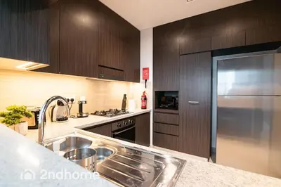 a kitchen with wooden cabinets and a stainless steel sink at Downtown Views 1 - Direct Access to Dubai Mall in Dubai