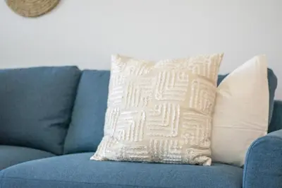a blue couch with a white pillow on it at StayShort - Elegant 2BR in Dubai Marina - Luxury Awaits You in Dubai