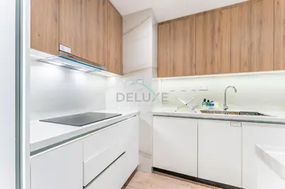 a white kitchen with wooden cabinets and a sink at Renovated 1BR with Partial Sea and City Views Near Beach, Elite Residence, Dubai Marina by Deluxe Holiday Homes in Dubai