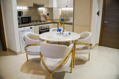 a kitchen with a white table and chairs in a kitchen at Vserve 2BR Perfect Blend of Luxury Comfort & Convenience in Dubai