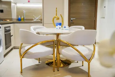 a kitchen with a white table and gold chairs at Vserve 2BR Perfect Blend of Luxury Comfort & Convenience in Dubai