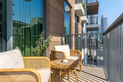 a balcony with wicker chairs and a table with a side table at Chic 1BR APT with Pool, Gym & Kid's Playground in Dubai
