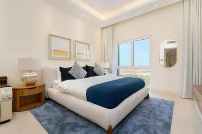 a white bedroom with a large bed and a window at Renovated Studios in Nature at Discovery Gardens in Dubai