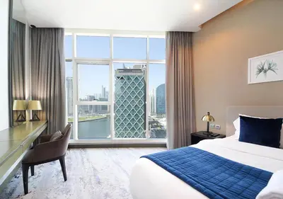 a bedroom with a bed and a desk and a large window at Stylish Studio in Damac Prive Canal-View Studio in Dubai