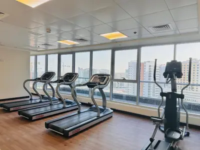 a gym with three treadmills in a room with windows at Airvistas Elevate Living 1BHK in Dubai