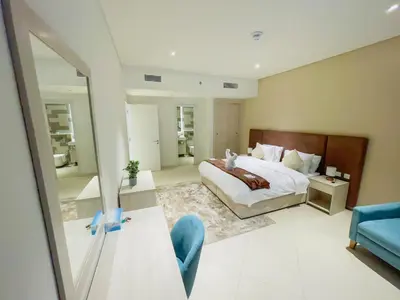 a bedroom with a large bed and a blue chair at Vserve Comfy & Relaxing 1 BDR Retreat At the Palm in Dubai
