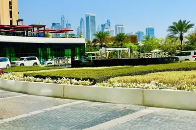 a park with white flowers in front of a building at Vserve Comfy & Relaxing 1 BDR Retreat At the Palm in Dubai