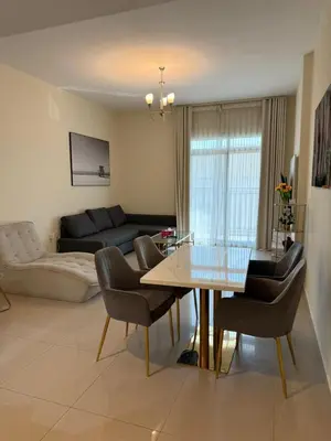 a living room with a table and chairs and a couch at Spacious 1BR Apartment with Balcony in JVC - JLiving in Dubai