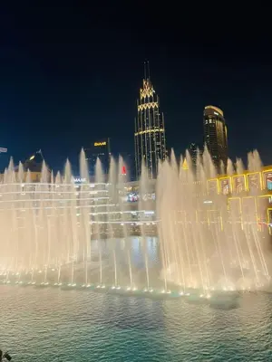 a fountain in the water with a city in the background at Souk Al Bahar Luxury stays near poolside with Burj Khalifa view by Norbu Holiday Homes in Dubai