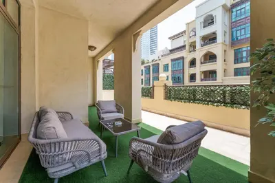 a balcony with chairs and a couch and a table at Souk Al Bahar Luxury stays near poolside with Burj Khalifa view by Norbu Holiday Homes in Dubai