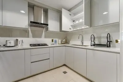 a white kitchen with white cabinets and a sink at Souk Al Bahar Luxury stays near poolside with Burj Khalifa view by Norbu Holiday Homes in Dubai