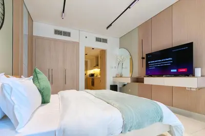 a bedroom with a large bed and a flat screen tv at Waterfront Studio with Burj Khalifa & Dubai Mall Access, Walk to Dubai Water Canal & Business Bay Metro in Dubai