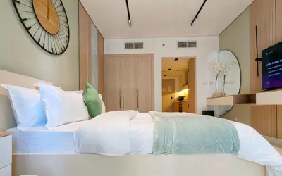 a bedroom with a white bed with a large clock on the wall at Waterfront Studio with Burj Khalifa & Dubai Mall Access, Walk to Dubai Water Canal & Business Bay Metro in Dubai