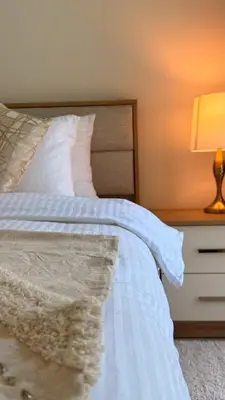 a bedroom with a white bed and a night stand with a lamp at Brand New Golf View - Luxe Nest at Dubai Hills one bedroom apartment in Dubai