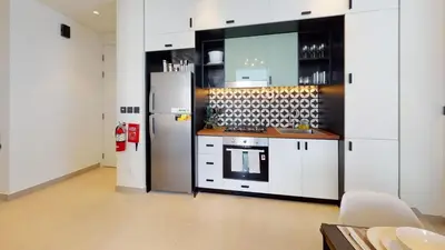 a kitchen with white cabinets and a refrigerator at Tranquil Oasis 2BR at Collective Dubai Hills in Dubai